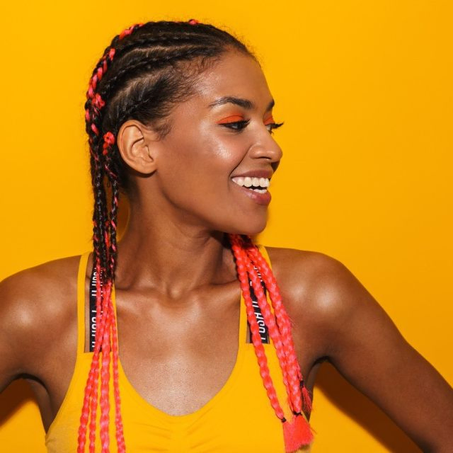 mujer sonriente con trenzas afro y fondo amarillo