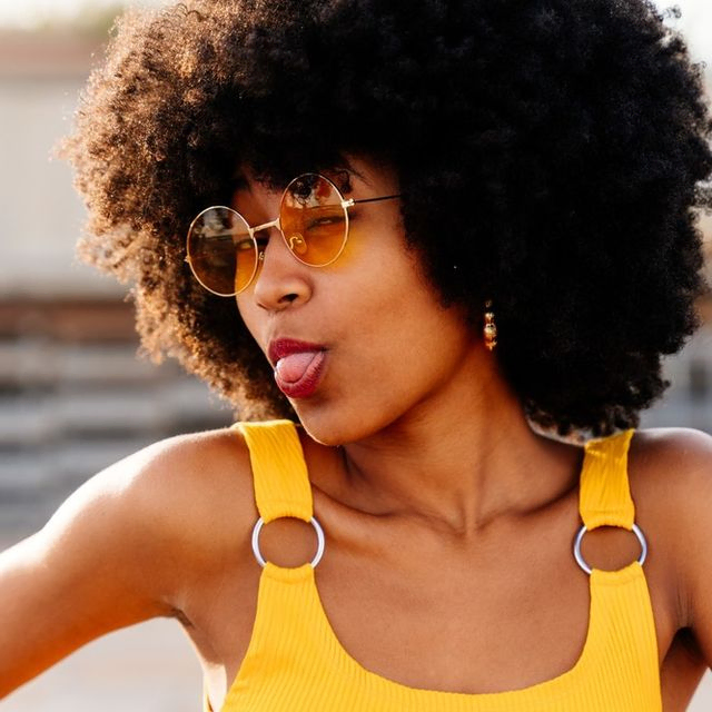 mujer de pelo afro y gafas saca lengua a camara